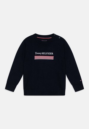 Maglione blu navy con maniche lunghe, collo rotondo, polsini e orlo a costine. Presenta il logo ricamato "Tommy HILFIGER" con strisce rosse e bianche.