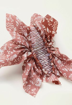 Klarer Kunststoff-Haarclip umwickelt mit rosa Stoff mit weißem Blumenmuster, dessen lose Stoffenden nach außen ragen.