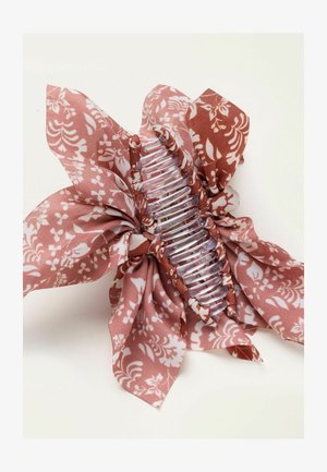 Klarer Kunststoff-Haarclip umwickelt mit rosa Stoff mit weißem Blumenmuster, dessen lose Stoffenden nach außen ragen.