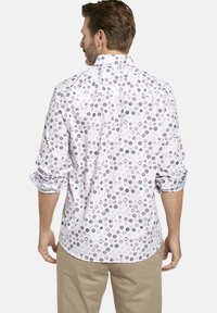 Weißes Hemd mit Knopfleiste, das ein mehrfarbiges Punktmuster in Rosa, Lila und Schwarz aufweist, mit hochgekrempelten Ärmeln und abgerundetem Saum.