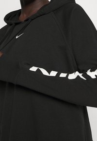 Czarna bluza z kapturem wykonana z bawełnianej mieszanki, z białym logo Nike na przodzie oraz dużym białym napisem "NIKE" na rękawie.