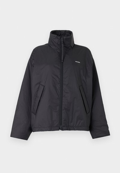 Μαύρο φουσκωτό μπουφάν με φερμουάρ, ψηλό γιακά, πλαϊνές τσέπες και μικρό λευκό λογότυπο στο αριστερό στήθος πάνω σε απλό φωτεινό φόντο.
