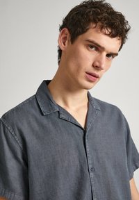 Short-sleeve, charcoal button-up shirt with a collar, made of lightweight fabric featuring a smooth texture and minimalistic design.