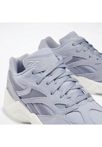 Ljust grå atletiska sneakers med en blandning av mocka och meshmaterial, med texturerade detaljer och en vadderad krage för komfort.