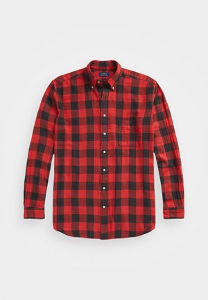 Pitkähihainen nappikiinnitteinen paita, jossa punamusta ruutukuvio ja etutasku rinnassa, esitettynä tasaisena valkoisella taustalla.