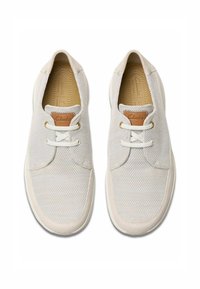 Valkoiset nauhattomat sneakerit, jotka on valmistettu verkkomateriaalista, ja joissa on vaaleanruskea nahka-akseli kielessä, teksturoitu kangas ja pehmeä kumipohja.