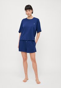 Mörkblå bomullsblandad loungeklädesset bestående av en löst sittande kortärmad topp och matchande shorts, med en liten logotypdetalj på toppen.