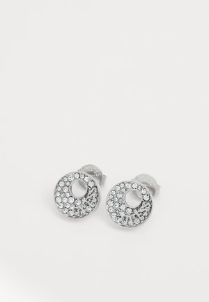 Boucles d'oreilles clous rondes en argent avec cristaux transparents et logo "GUESS" courbé le long du bord inférieur de chaque boucle.