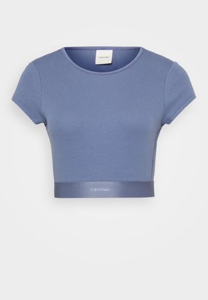 Camiseta cropped azul clara com mangas curtas e textura canelada. Apresenta uma faixa elástica com marca na bainha. Decote redondo.