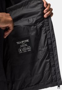 Zwarte geïsoleerde jas interior, met Texapore-label en symbolen voor waterdichte, ademende en winddichte eigenschappen. Smooth textuur.