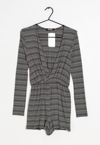 Svart och vit randig långärmad jumpsuit med djup V-ringning, figursydd midja och löst sittande shorts. Slitstarkt, elastiskt tyg.