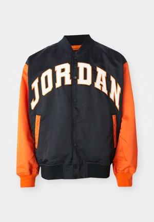 Veste de varsity noire et orange avec "JORDAN" en grandes lettres blanches et oranges sur la poitrine, fermeture à boutons-pression à l'avant et poignets côtelés.