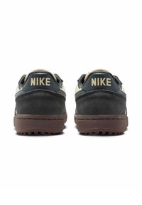 Sneakers Nike z ciemnoszarym zamszowym cholewką, kremowymi akcentami i brązową gumową podeszwą. Posiadają charakterystyczne logo "Nike" na pięcie.