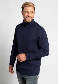 Námornícky modré tričko s dlhým rukávom a rolákom vyrobené z mäkkej tkaniny, s voľným strihom a minimalistickým dizajnom bez výrazných vzorov.