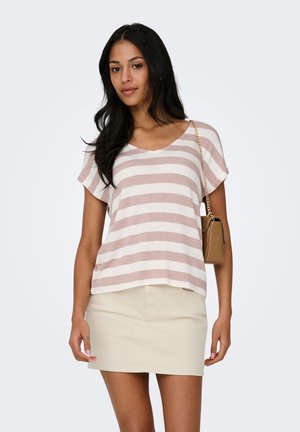 Vrouw met lang zwart haar, gekleed in een beige-wit gestreept kortärmelig shirt, beige rok en een schoudertas met een gouden kettingriem.