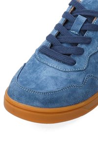 Blaue Wildledersneaker mit einer glatten Textur, kontrastierenden marineblauen Schnürsenkeln und einer braunen Gummisohle mit dezenten Stickdetails.