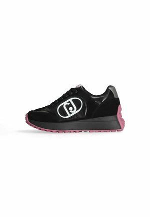 Sneaker nera con texture lucida e scamosciata, un logo prominente in bianco e una suola rosa texturizzata. Presenta un sistema di lacci piatti.
