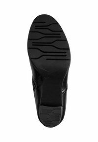 Semelle de chaussure noire avec une surface texturée comportant des rainures horizontales et verticales pour une meilleure adhérence. Forme arrondie avec un talon légèrement surélevé.