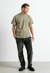 Kaki bomull t-skjorte med korte ermer, kombinert med mørkegrå cordbukser og svarte ankelstøvletter. Enkel og avslappet passform.