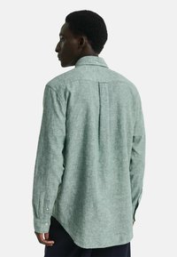 Lichtgroen overhemd met lange mouwen, een gestructureerde afwerking, een button-down kraag en een plooidetail aan de achterkant. Voorzien van knoopmanchetten.