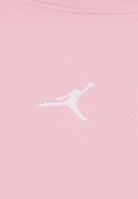 Lyserød atletisk skjorte med en hvid broderet Jumpman-logo, med en glat tekstur og tætsiddende design.