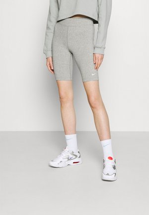 Shorts de vélo gris ajustés, texture lisse, associés à un sweat-shirt court gris clair. Baskets Nike blanches avec des accents multicolores et chaussettes.