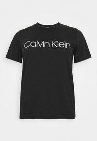 Černé bavlněné tričko s bílým logem "Calvin Klein" v moderním písmu. Krátké rukávy a kulatý výstřih, hladká textura.