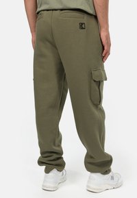 Olijfgroene cargobroek van een zachte katoenmix, met zijzakken, elastische boorden en een klein logo geborduurd op de achterkant.