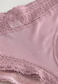 Roza donje rublje s čipkastim rubom, napravljeno od glatkog materijala. Ima rebrastu teksturu i složene čipkaste detalje duž struka i otvora za noge.