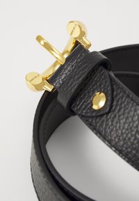 Ceinture en cuir noir avec une finition texturée, dotée d'une boucle en or brillant et de détails assortis. Comprend un passant en cuir sécurisé et un accent snap.