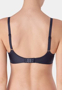 Marineblauwe beha met dunne verstelbare bandjes, getande randen en een haak- en oogsluiting aan de achterkant. Gladde stof met minimale ontwerpdetails.