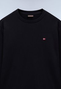 Svart genser med rund hals, ribbet krage og et lite brodert norsk flagg på venstre bryst. Myk stofftekstur.