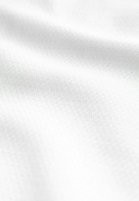 Teksturowana biała tkanina z subtelnym wzorem, prezentująca gładką powierzchnię i miękki wygląd, idealna do różnych zastosowań tekstylnych.