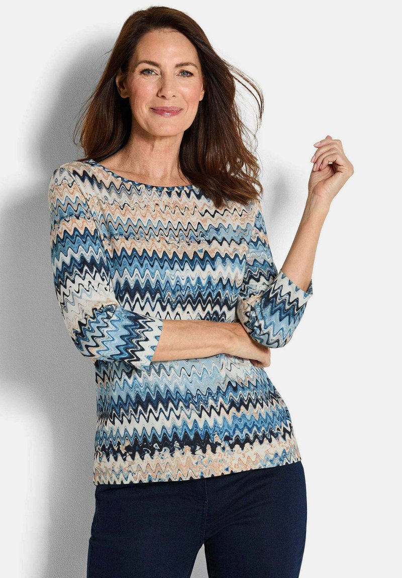 Langarmoberteil mit Wellenmuster in Blau, Creme und Rostfarben. Hergestellt aus strukturiertem Stoff, mit rundem Ausschnitt und enganliegenden Ärmeln.