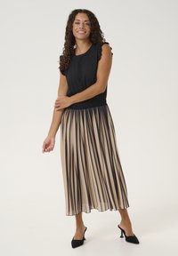 Črna majica z nabranimi rokavi, v kombinaciji z nabranim bež krilom z navpičnimi črnimi črtami. Črne špičaste petke za zaključek videza.