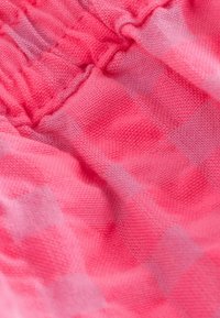 Roosa kanga lähedalt vaadatuna, millel on elastne õmblus ja peen teemantmuster, näidates tekstuuri ja kogutud detaili.