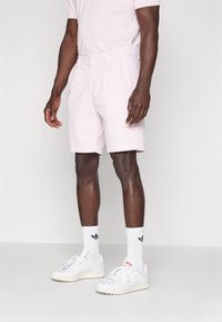 Ljusrosa shorts med skräddarsydd passform, med bältesöglor och framfåll, i kombination med vita sneakers och sportstrumpor med logo.