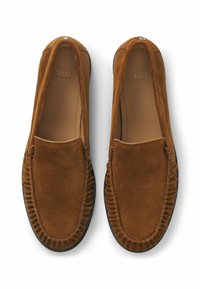 Καφέ σουέτ λόφερ με πτυχωτό σχέδιο, στρογγυλή μύτη και μαύρη καουτσούκ σόλα. Διακοσμημένα με λογότυπο στην επάνω πλευρά.