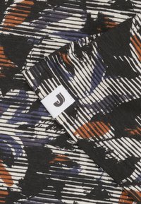 Zwarte stof met een gestreept patroon van oranje, blauw en witte abstracte vormen. Bevat een wit label met een zwart "J"-logo.