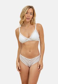 Ensemble de lingerie en dentelle blanche comprenant un soutien-gorge triangle et des culottes assorties. Motifs floraux et géométriques, bretelles délicates et accents assortis.