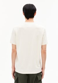 Kurzärmeliges, cremefarbenes T-Shirt aus Baumwolle mit Rundhalsausschnitt und lässiger Passform, das eine glatte, weiche Textur aufweist.