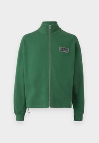 Groene ritssluiting sweatshirt met opstaande kraag, gemaakt van zachte stof, met een klein merkembleem op de linkerkant van de borst en ribgebreide manchetten.