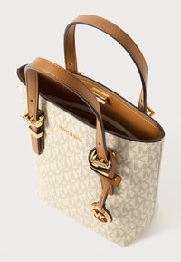 Canvas tote taske med brune læderstropper, gyldent hardware og en beige mønstret yderside. Har et rummeligt interiør med en glat foring.