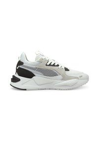 Zapatilla deportiva blanca con parte superior de malla y ante, acentos negros, suela texturizada y cordones planos. Presenta un diseño moderno y una construcción en capas.