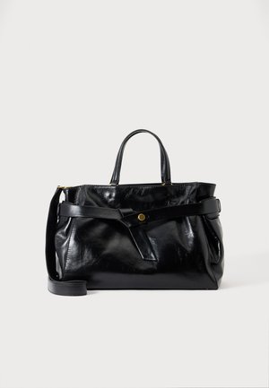 Sac à main en cuir noir brillant avec deux poignées, une sangle avant avec un bouton doré et une bandoulière ajustable, présenté sur fond blanc.