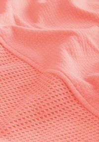 Coral textured fabric with a honeycomb pattern and smooth area; soft, lightweight material draping in gentle folds.