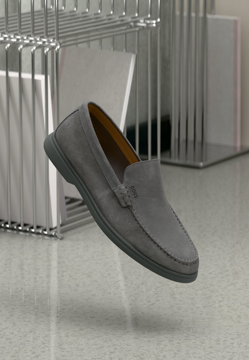 Zapatos de ante gris sin cordones con una textura suave, costuras tonales y una suela de goma flexible. Presentan el logotipo grabado en el lateral.