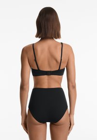 Černý bikini set se skládá z topu s krátkým rukávem a nastavitelnými ramínky a uzávěrem na háček, doplněný o vysoké kalhotky. Hladká textura po celém povrchu.