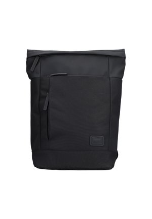 Sac à dos noir en tissu durable avec une fermeture éclair sur le dessus et une poche avant. Présente un design épuré, un matériel minimal et des accents texturés.