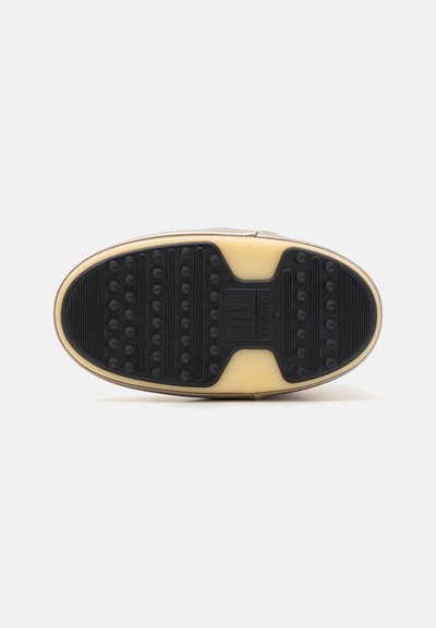 Black rubber sole with textured grip and circular accents. Beige midsole and a light brown upper, stitched along the edges.